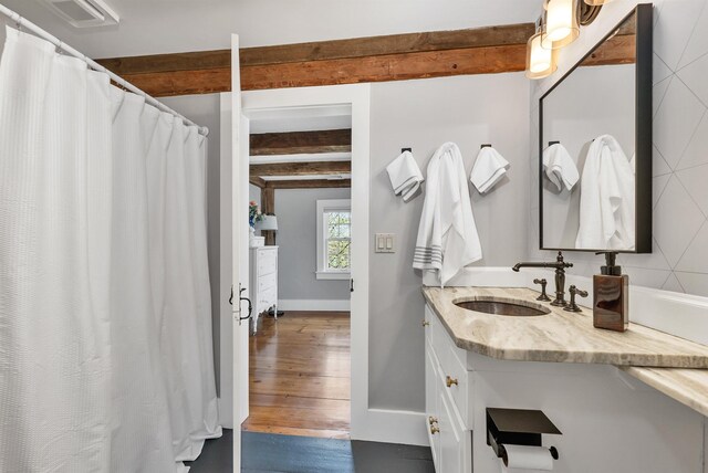 bathroom with vanity, baseboards, and beamed ceiling