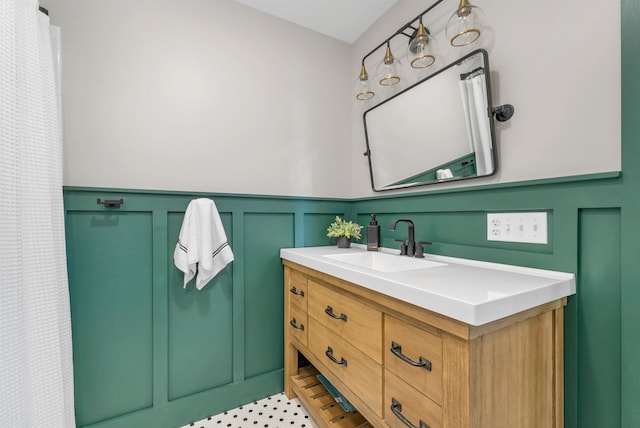 bathroom with a decorative wall, wainscoting, and vanity