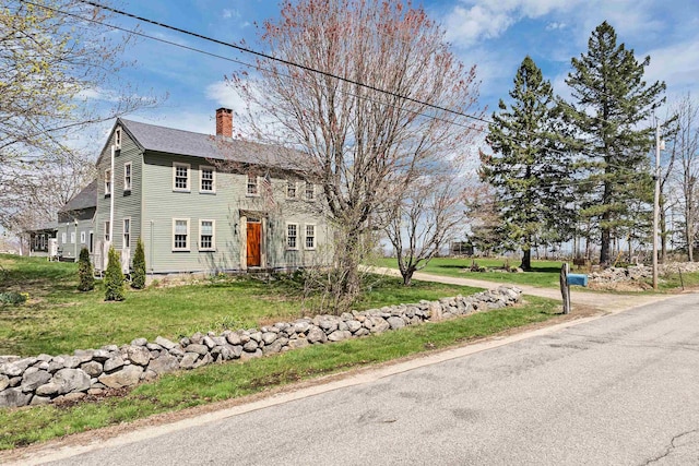 colonial home featuring a chimney and a front yard