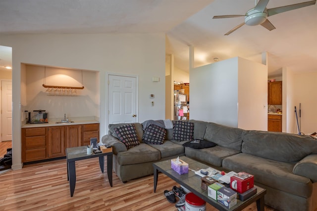 living room featuring light wood-style floors, ceiling fan, bar area, and high vaulted ceiling