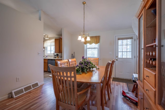 dining room featuring visible vents, a wealth of natural light, an inviting chandelier, and wood finished floors