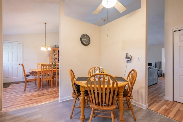 dining room featuring baseboards, ceiling fan with notable chandelier, lofted ceiling, and wood finished floors