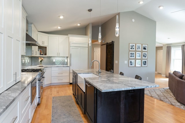 kitchen featuring stainless steel stove, a barn door, a sink, and lofted ceiling