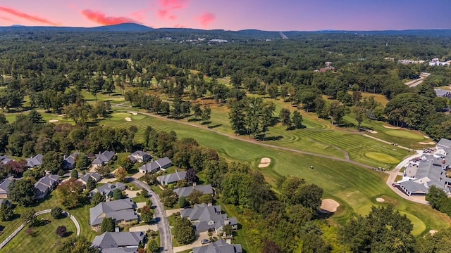 aerial view at dusk featuring view of golf course, a mountain view, and a forest view