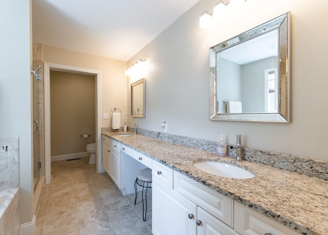 bathroom with a sink, a stall shower, toilet, and double vanity