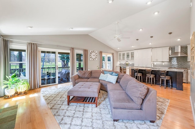 living room with ceiling fan, vaulted ceiling, recessed lighting, and light wood-style flooring