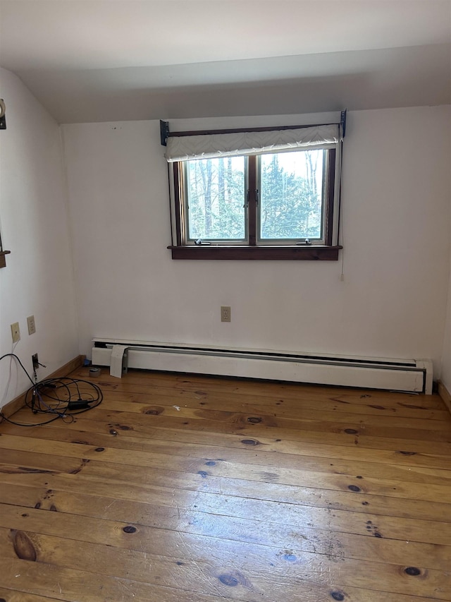spare room featuring baseboards, a baseboard radiator, and wood-type flooring