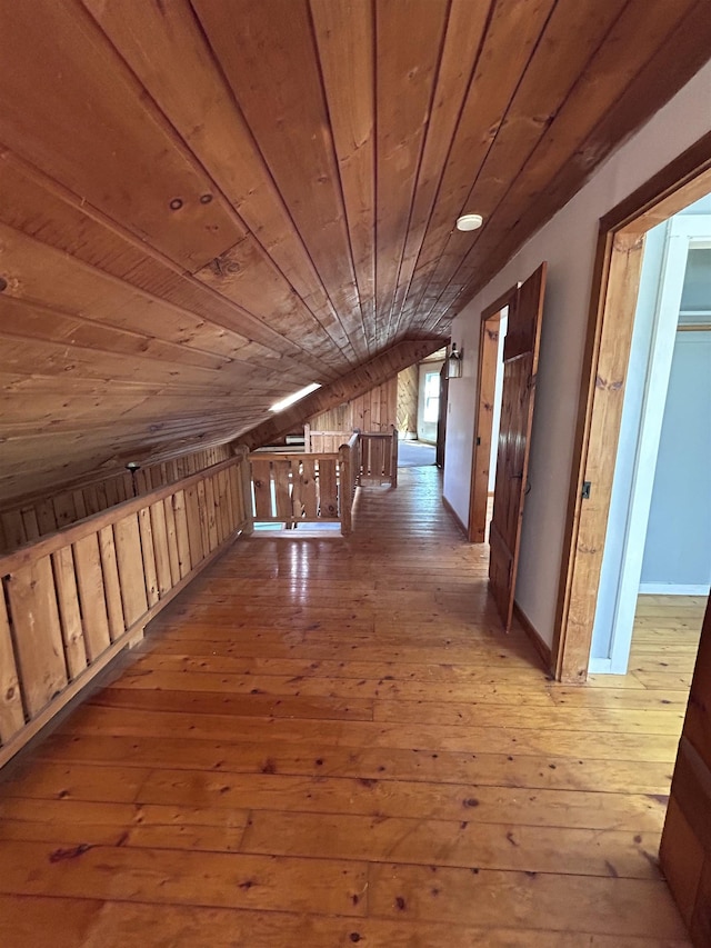 corridor with an upstairs landing, wood ceiling, lofted ceiling, and hardwood / wood-style floors