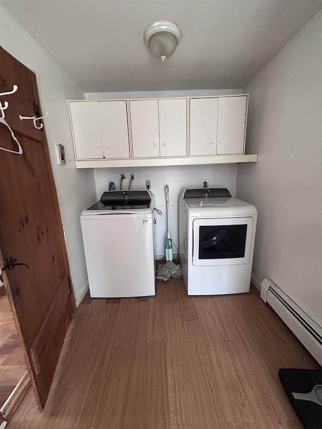 clothes washing area with wood finished floors, baseboard heating, cabinet space, and washer and clothes dryer