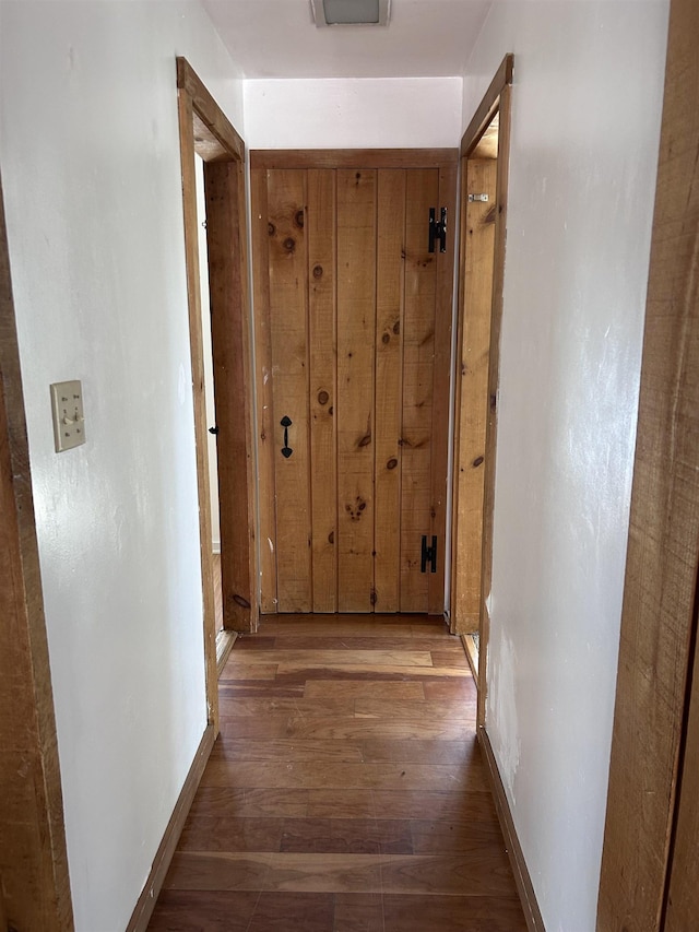 corridor with baseboards and wood finished floors