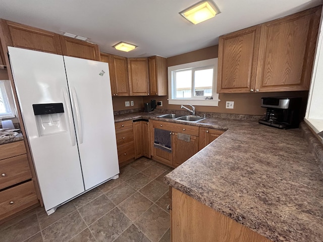 kitchen with brown cabinetry, a sink, dark countertops, and white fridge with ice dispenser
