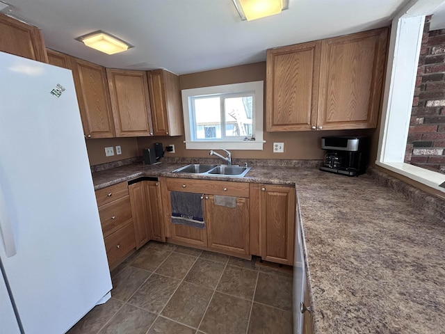 kitchen with a sink, freestanding refrigerator, and brown cabinets