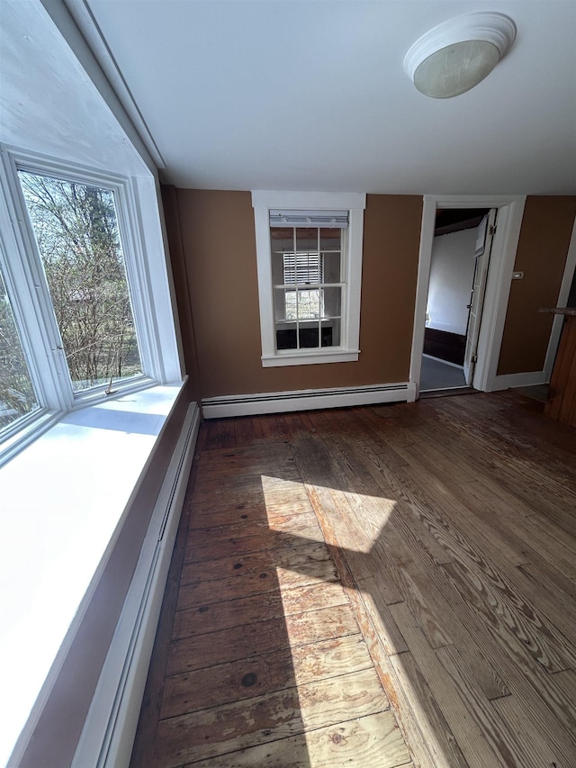 unfurnished room featuring baseboards, baseboard heating, and hardwood / wood-style floors