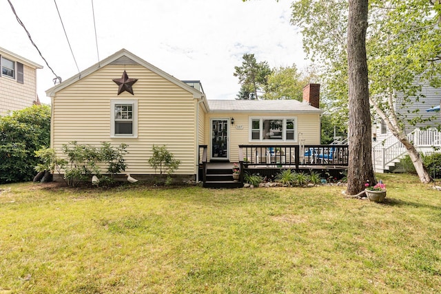 rear view of property with a wooden deck, a yard, and a chimney