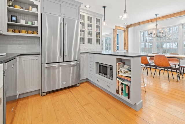 kitchen featuring open shelves, dark countertops, appliances with stainless steel finishes, and an inviting chandelier