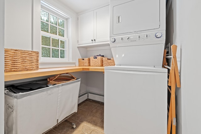 washroom with cabinet space, stacked washer / dryer, tile patterned flooring, and a baseboard heating unit