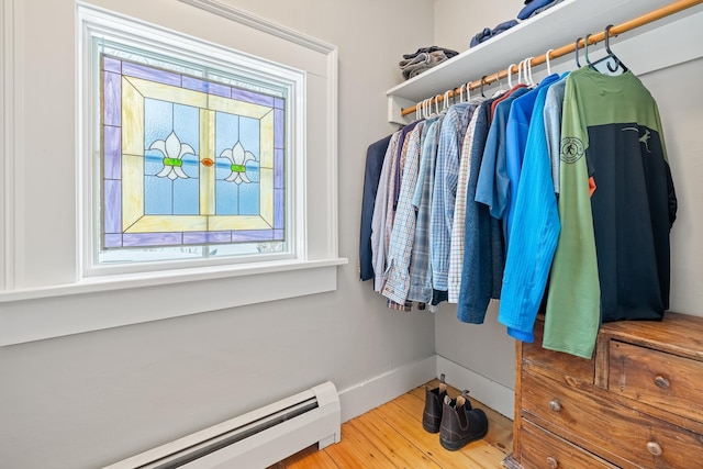walk in closet with wood finished floors and baseboard heating