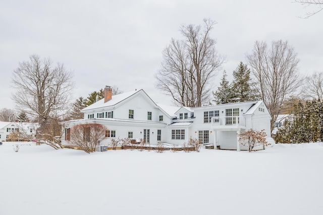 snow covered rear of property featuring a chimney