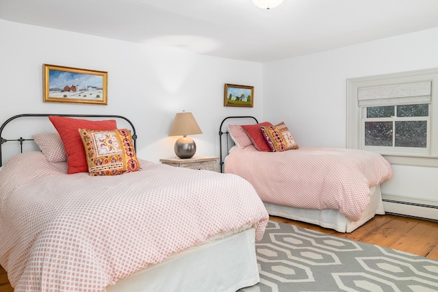bedroom featuring a baseboard heating unit and wood finished floors