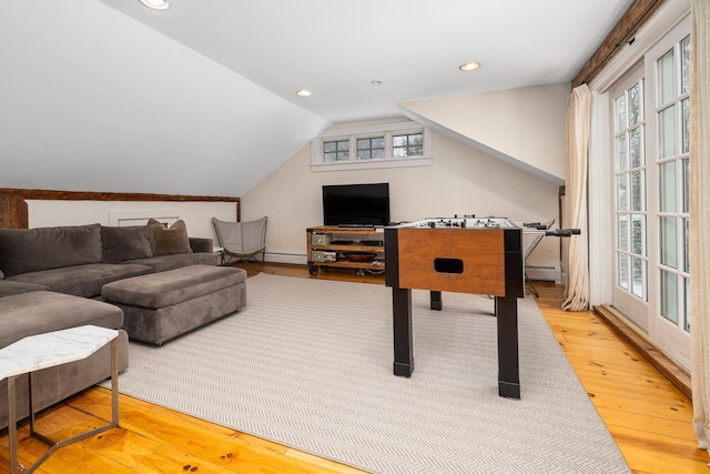 playroom featuring a wealth of natural light, vaulted ceiling, wood finished floors, and a baseboard heating unit