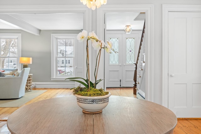 foyer entrance featuring baseboards, stairs, a healthy amount of sunlight, and wood-type flooring