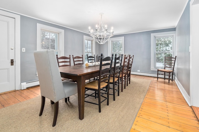 dining area featuring light wood finished floors, ornamental molding, a notable chandelier, and baseboard heating