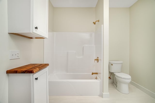 bathroom featuring toilet, baseboards, and  shower combination
