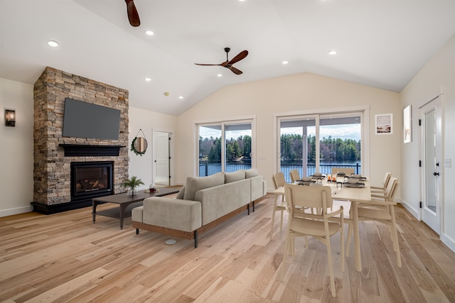 living area with a ceiling fan, a stone fireplace, light wood finished floors, lofted ceiling, and recessed lighting