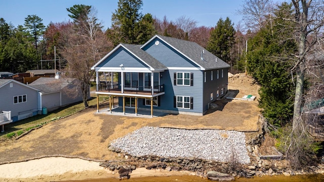 rear view of house featuring a patio, a shingled roof, and a wooden deck