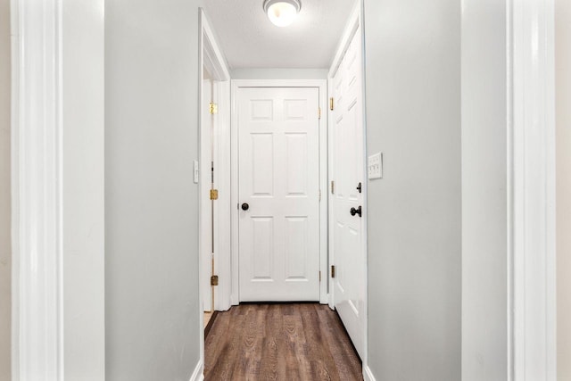 corridor with baseboards, dark wood-style floors, and a textured ceiling