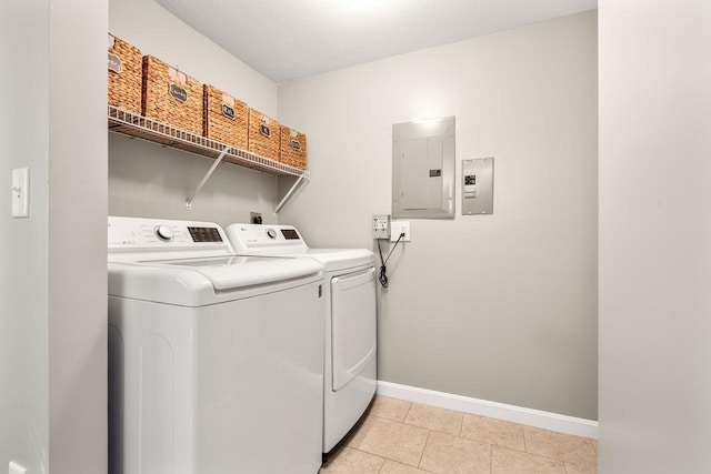clothes washing area featuring laundry area, light tile patterned flooring, washer and dryer, baseboards, and electric panel