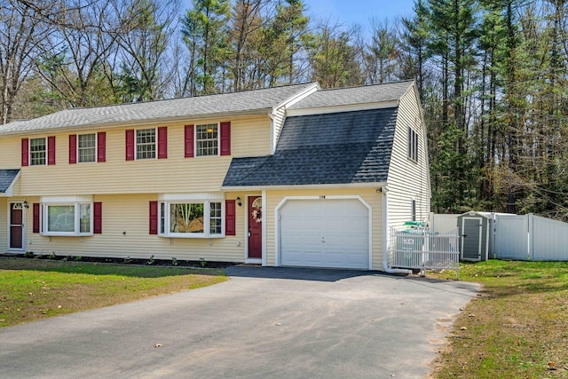 view of front of house with fence, a front lawn, a garage, a gate, and driveway