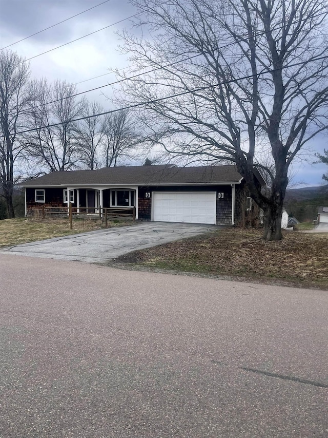 ranch-style house with covered porch, an attached garage, and driveway