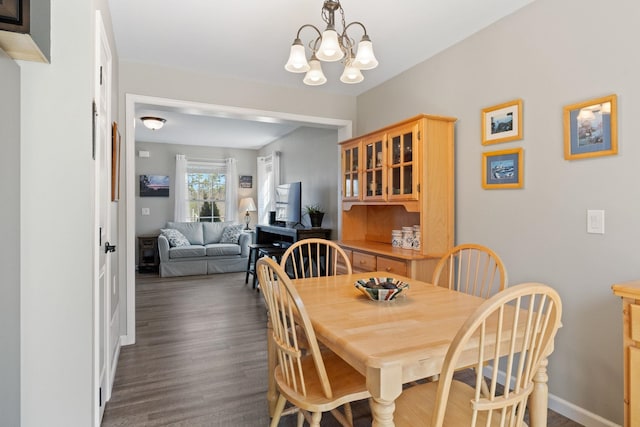 dining space with baseboards, an inviting chandelier, and dark wood-type flooring