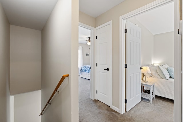 corridor with baseboards, carpet, and an upstairs landing