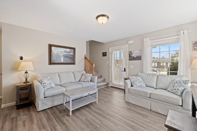 living room featuring stairs, baseboards, plenty of natural light, and wood finished floors