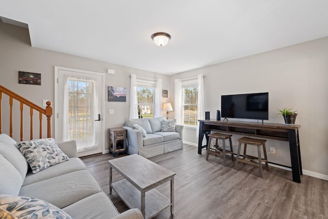 living area featuring baseboards, wood finished floors, and stairway