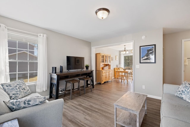 living room featuring baseboards, a notable chandelier, and wood finished floors