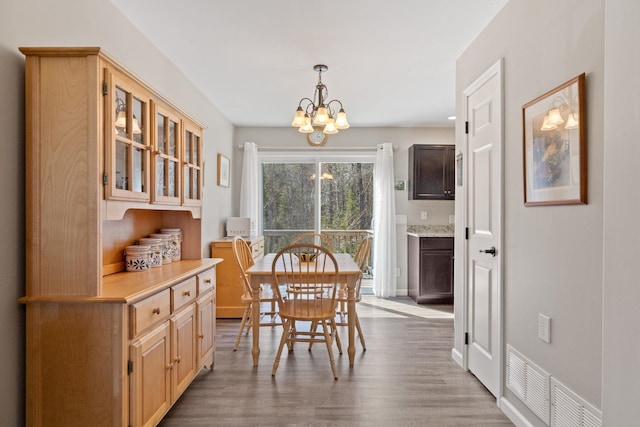 dining room featuring visible vents, baseboards, wood finished floors, and a notable chandelier