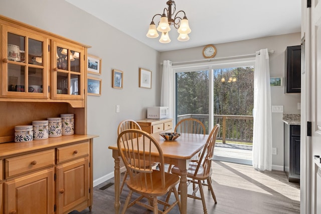 dining space featuring an inviting chandelier, baseboards, and dark wood finished floors