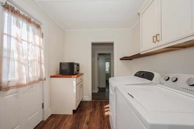 washroom featuring crown molding, baseboards, dark wood-type flooring, washing machine and clothes dryer, and cabinet space