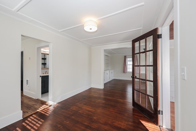 spare room with wood-type flooring, baseboards, and crown molding