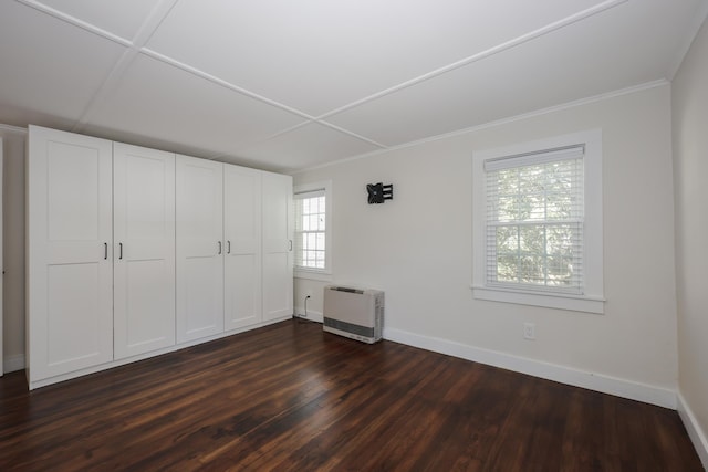 unfurnished bedroom featuring crown molding, baseboards, heating unit, and dark wood-type flooring