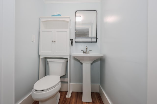 half bathroom with baseboards, toilet, and wood finished floors