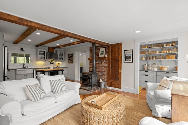 living room featuring recessed lighting, baseboards, a wood stove, and light wood finished floors