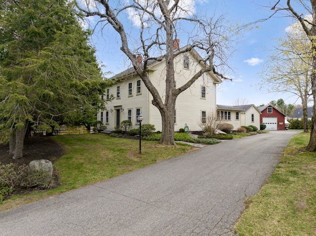 view of front facade with a garage, a chimney, driveway, and a front yard