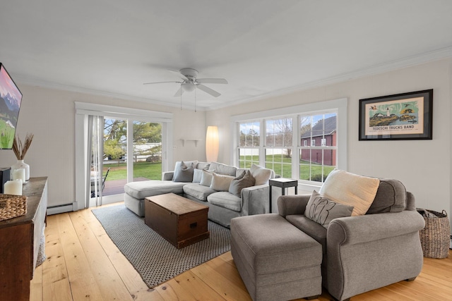 living area with crown molding, a ceiling fan, a baseboard heating unit, and light wood-style flooring