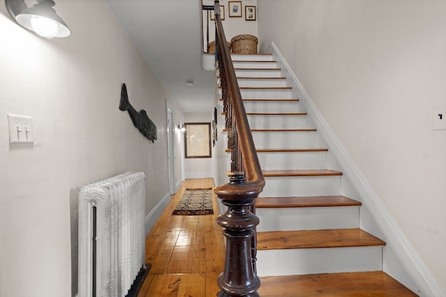 stairs featuring radiator and hardwood / wood-style flooring