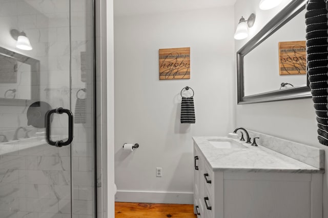 bathroom with vanity, baseboards, a stall shower, and wood finished floors
