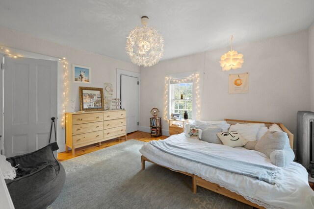 bedroom with light wood-style floors and a notable chandelier